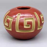 A red seed pot carved with a band of outlined square spirals around the shoulder
 by Anita Suazo of Santa Clara