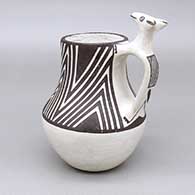 A black-on-white mug with a painted geometric design and an applique and painted animal handle detail