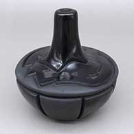 Black jar with a tall neck and carved with an avanyu design around the upper surface