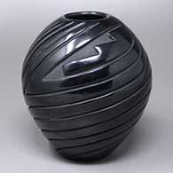 A black seed pot carved with a spiraling geometric design