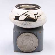 A miniature black-on-white bowl decorated with a reclining kokopelli design