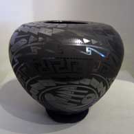 A black-on-black jar with a fish and geometric design