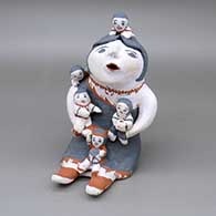 A grandmother storyteller figure with 5 children, a jar and a drum