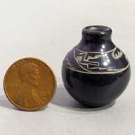 Miniature black jar with a sgraffito avanyu design