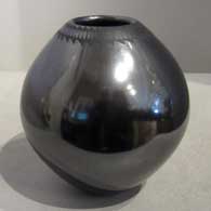 Necklace of black on black Paquime designs on a highly polished black jar