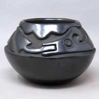 A black bowl carved with an avanyu and geometric design