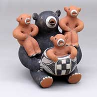 A bear storyteller figure with three cubs