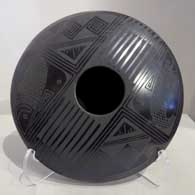 Bird element, fish and geometric design in matte black on a polished black flying saucer jar