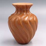 A red jar with a flared rim and carved with a curving melon design