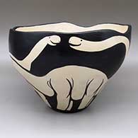An open black-on-white bowl decorated on the outside with dinosaur forms