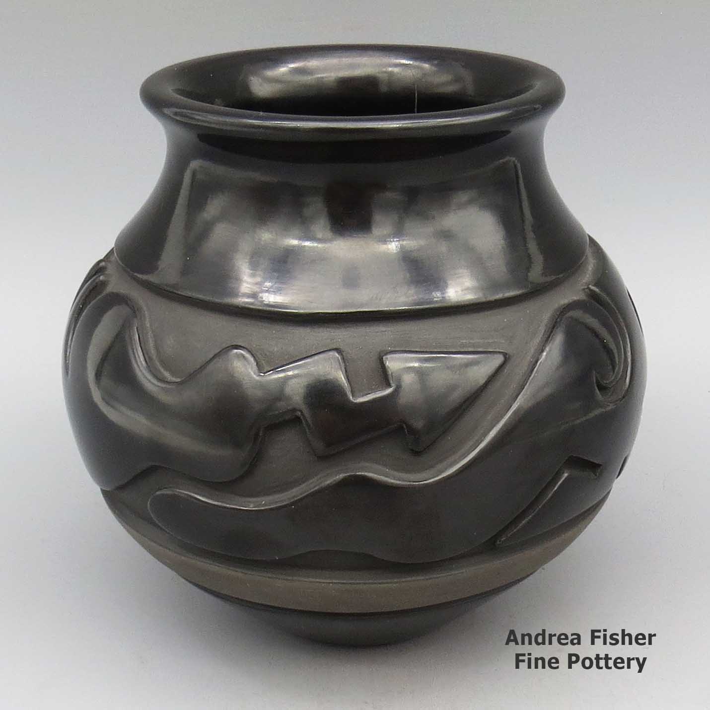 Black jar with flared rim and carved stylized avanyu design made by Nathan Youngblood of Santa Clara