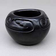 Small black jar with a rounded, triangular opening and a three-panel carved geometric design
 by Toni Roller of Santa Clara