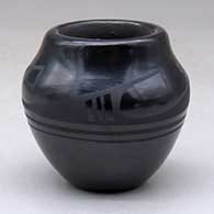 Click for a larger view A small black on black jar decorated with a four panel geometric design around the shoulder
by Helen Gutierrez of San Ildefonso