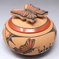 Small polychrome jar with a sculpted butterfly handle on the lid and a painted 4-panel butterfly and geometric design around the body of the piece
 by Mary Louise Eteeyan of Jemez