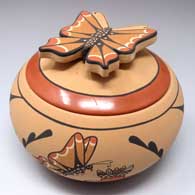 Small polychrome jar with a sculpted butterfly handle on the lid and a 4-panel butterfly and geometric design around the body of the piece
 by Mary Louise Eteeyan of Jemez