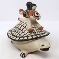 2 children sitting on the back of a turtle figure
 by Unknown of Cochiti