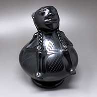 A black human effigy on a polished black jar decorated with a matte black geometric design
 by Rosa Quezada of Mata Ortiz and Casas Grandes