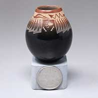A miniature black jar with a sienna rim and a sgraffito avanyu, ring-of-feathers and geometric design
 by Kevin Naranjo of Santa Clara