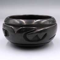 Black bowl carved on the outside with a stylized avanyu design
 by Stella Chavarria of Santa Clara