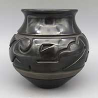 Black jar with flared rim and carved stylized avanyu design, click or tap to see a larger version