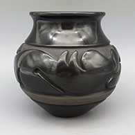 Black jar with flared rim and carved stylized avanyu design, click or tap to see a larger version