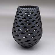 A black jar with a notched rim and decorated with a spiraling pattern of rhomboid cutouts
 by Mariano Quezada of Mata Ortiz and Casas Grandes