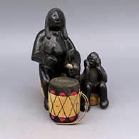 Black figure of man and child, includes wooden log seat, cork seat, wood drumstick, and wood and leather drum
 by Jose Victor Aguilar of San Ildefonso