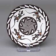 Small polychrome plate with a painted lizard, fine line, and geometric design on top and an applique ladybug detail on bottom
 by Carolyn Concho of Acoma