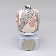 Miniature polychrome jar with a cylindrical shape, a geometric cut opening, and a geometric design
 by Carla Martinez of Mata Ortiz and Casas Grandes
