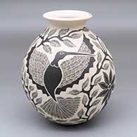 A black-on-white jar with a rolled lip and decorated with a sgraffito bird, branch and leaf design
 by Lorenza Quezada of Mata Ortiz and Casas Grandes