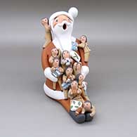Polychrome Santa Claus storyteller with ten children, a soccer ball, a football, a basketball, a baseball, a candy cane, and wrapped presents
 by Diane Lucero of Jemez