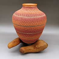 Large polychrome jar with a slightly flared opening, a coiled design, and a driftwood stand
 by Jamie Zane Smith of Wyandot