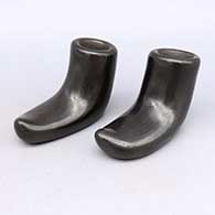 Two piece black candlestick holders in the shape of shoes
 by Reycita Cosen of Santa Clara