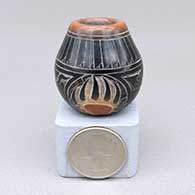 Miniature black jar with a sienna spot and rim and a sgraffito bear paw, avanyu, feather ring and geometric design
 by Kevin Naranjo of Santa Clara