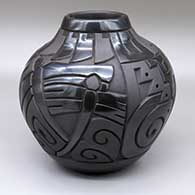 A black-on-black jar carved with a shard, dragonfly, spiral and geometric design
 by Daniel Begay of Santa Clara