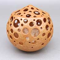 Titled Water Drops, a micaceous gold sculptural holey pot with circular cut-outs
 by Hubert Candelario of San Felipe