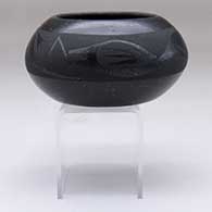 A black-on-micaceous-black bowl decorated with an avanyu design above the shoulder
 by Johnny Cruz of San Ildefonso