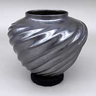 A glossy black jar with a repousse swirl melon design