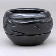 A black bowl carved with an avanyu design around the body