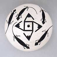 A black-on-white seed pot decorated with a whirling log, lizard and geometric design