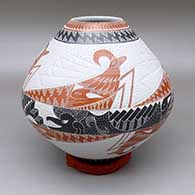 A polychrome jar decorated with a sgraffito and lightly carved ram, bird, and geometric design against a textured background