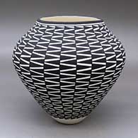 A black on white jar decorated around the body with a geometric design