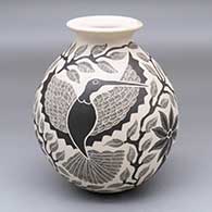 A black-on-white jar with a rolled lip and decorated with a sgraffito bird, branch and leaf design
