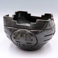 A black prayer bowl with a squared rim and carved around the body with a 4-panel katsina and geometric design