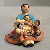 A sitting grandmother storyteller wearing a skirt and singing to three children