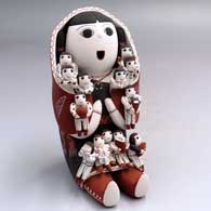 A grandmother storyteller figure wearing a manta and holding 13 children