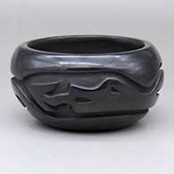 A black bowl carved around the body with an avanyu design