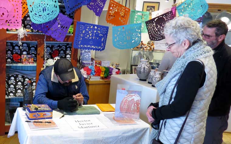 Hector Javier Martinez doing some sgraffito work while visitors look on