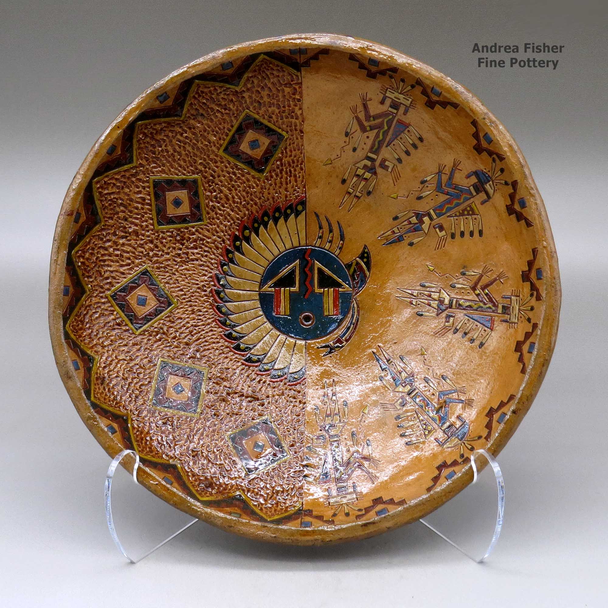 Click or tap to see a larger view A shallow polychrome bowl decorated with a sgraffito and painted yeibichai, sun shield, feather and geometric design made by Nancy Yazzie of Dineh