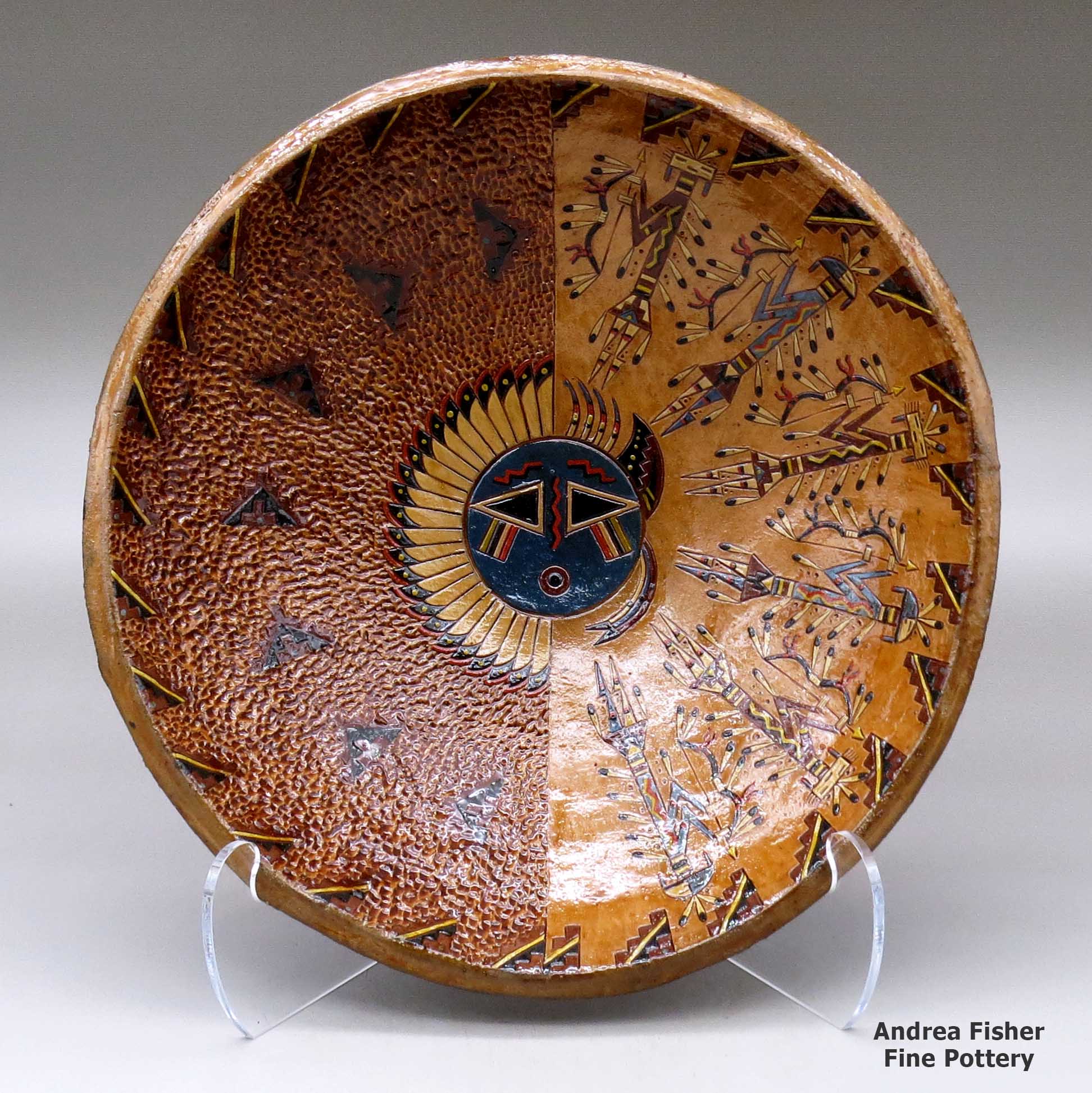 Click or tap to see a larger view A wide, open polychrome bowl decorated inside with a sgraffito and painted Yeibichai, sun, feather, star and geometric design, and decorated outside with a geometric design made by Nancy Yazzie of Dineh